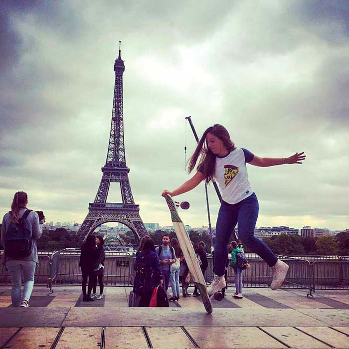 Woman doing trick on Komodo TT longboard in front of Eiffel Tower